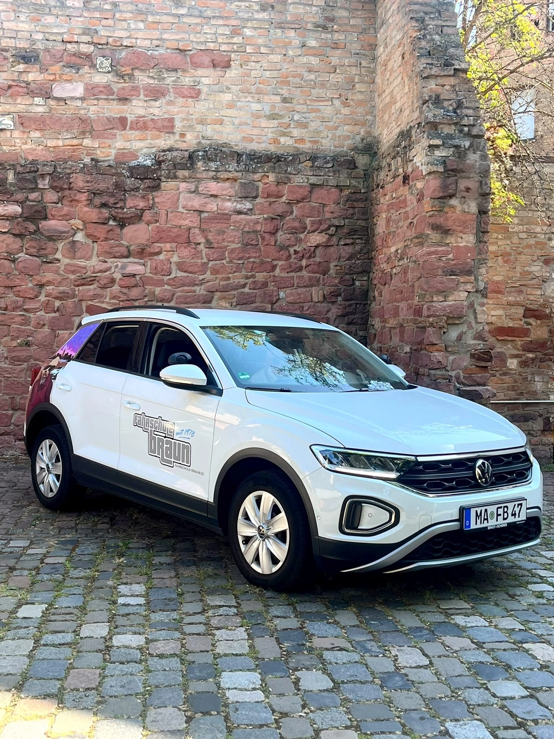 Weißer VW T-Roc der Fahrschule Braun mit Fahrschulbeschriftung